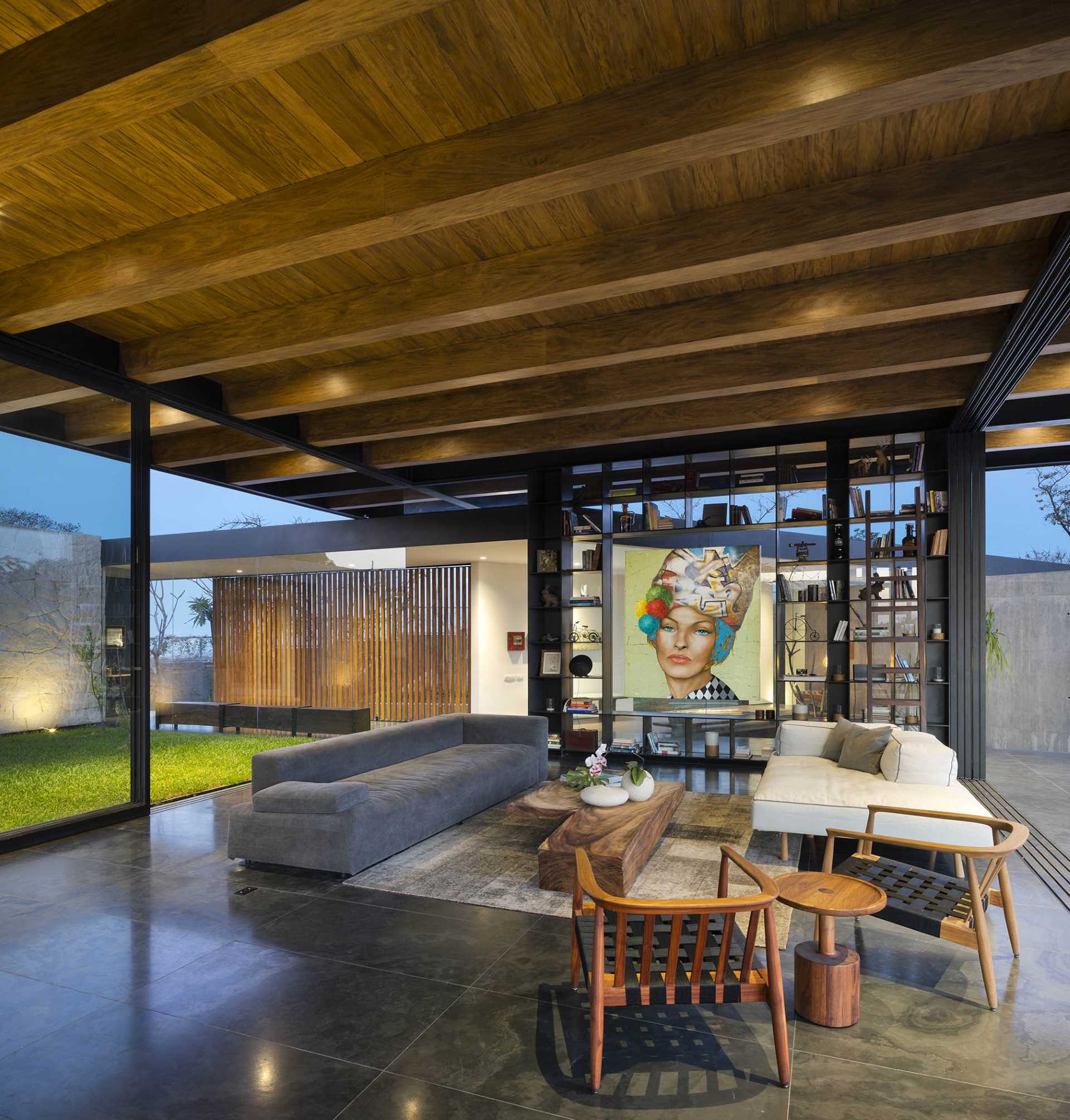 A modern living room with exposed structural elements, that opens to the outdoors and swimming pool.