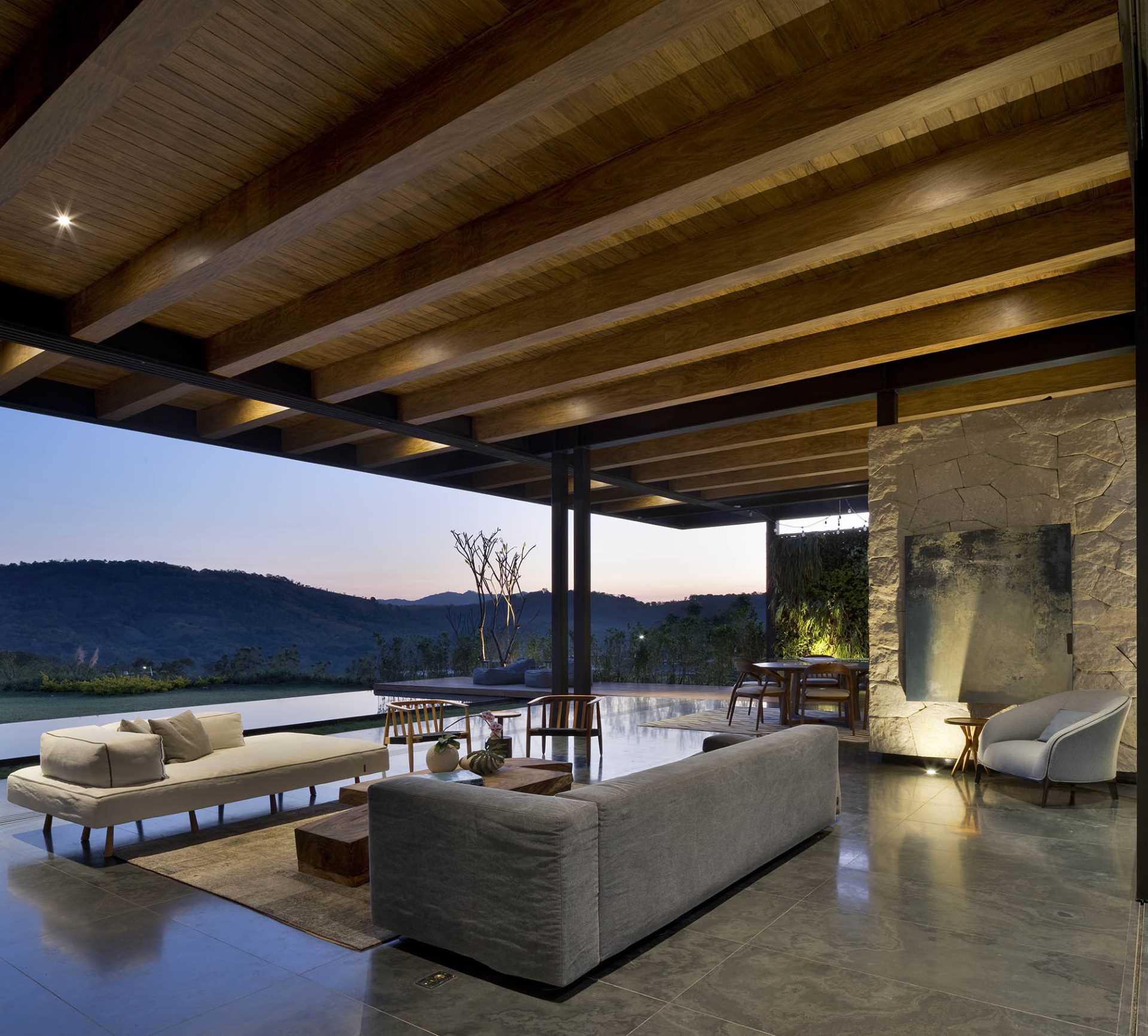 A modern living room with exposed structural elements, that opens to the outdoors and swimming pool.