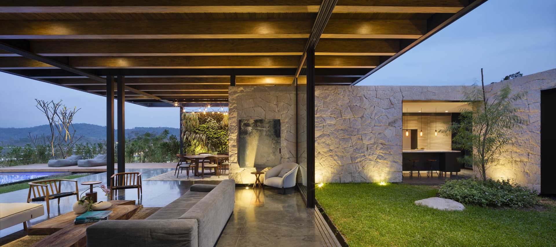 A modern living room with exposed structural elements, that opens to the outdoors and swimming pool.