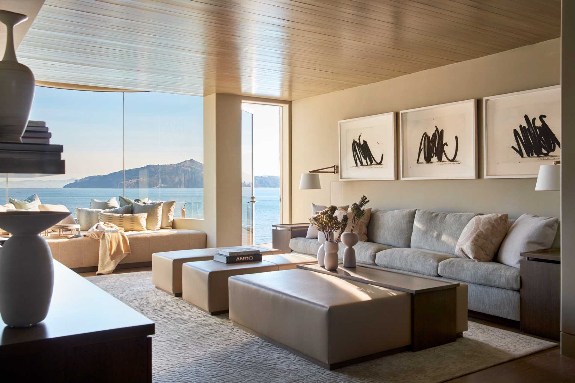 An upholstered bench in a living room fits perfectly beneath the curved windows in this contemporary interior.