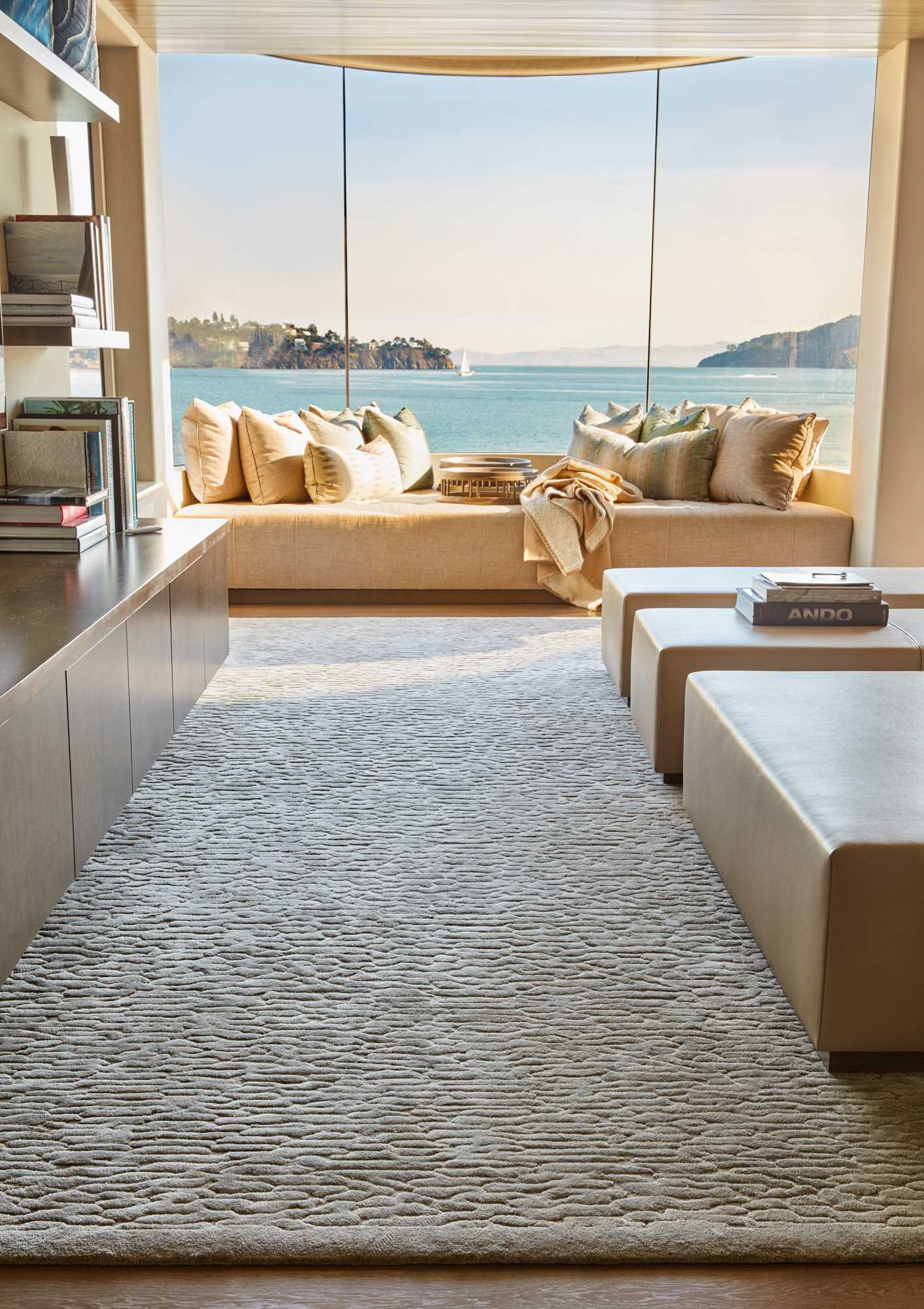 An upholstered bench fits perfectly beneath the curved windows in this contemporary interior.