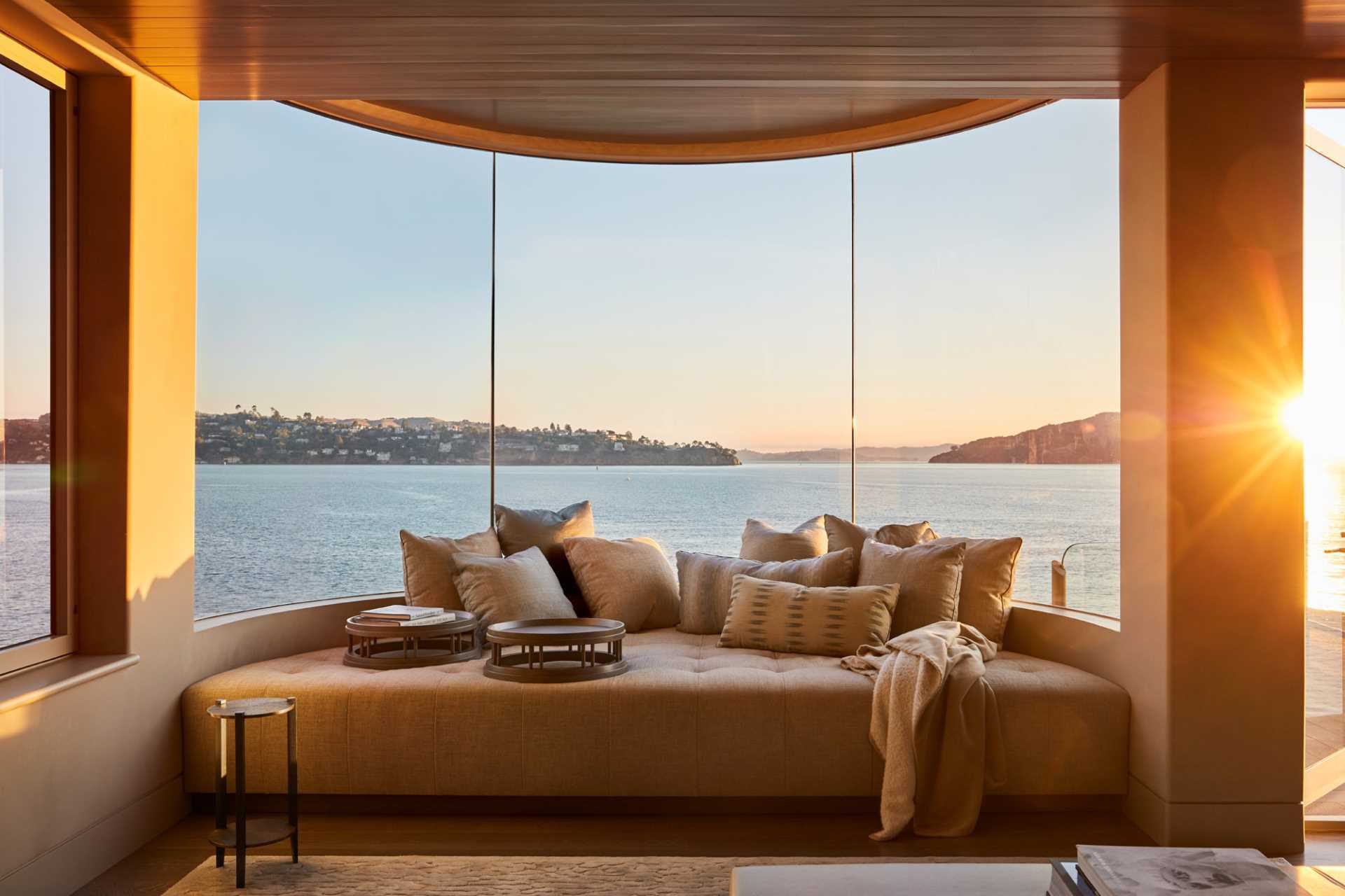 An upholstered bench fits perfectly beneath the curved windows in this contemporary interior.