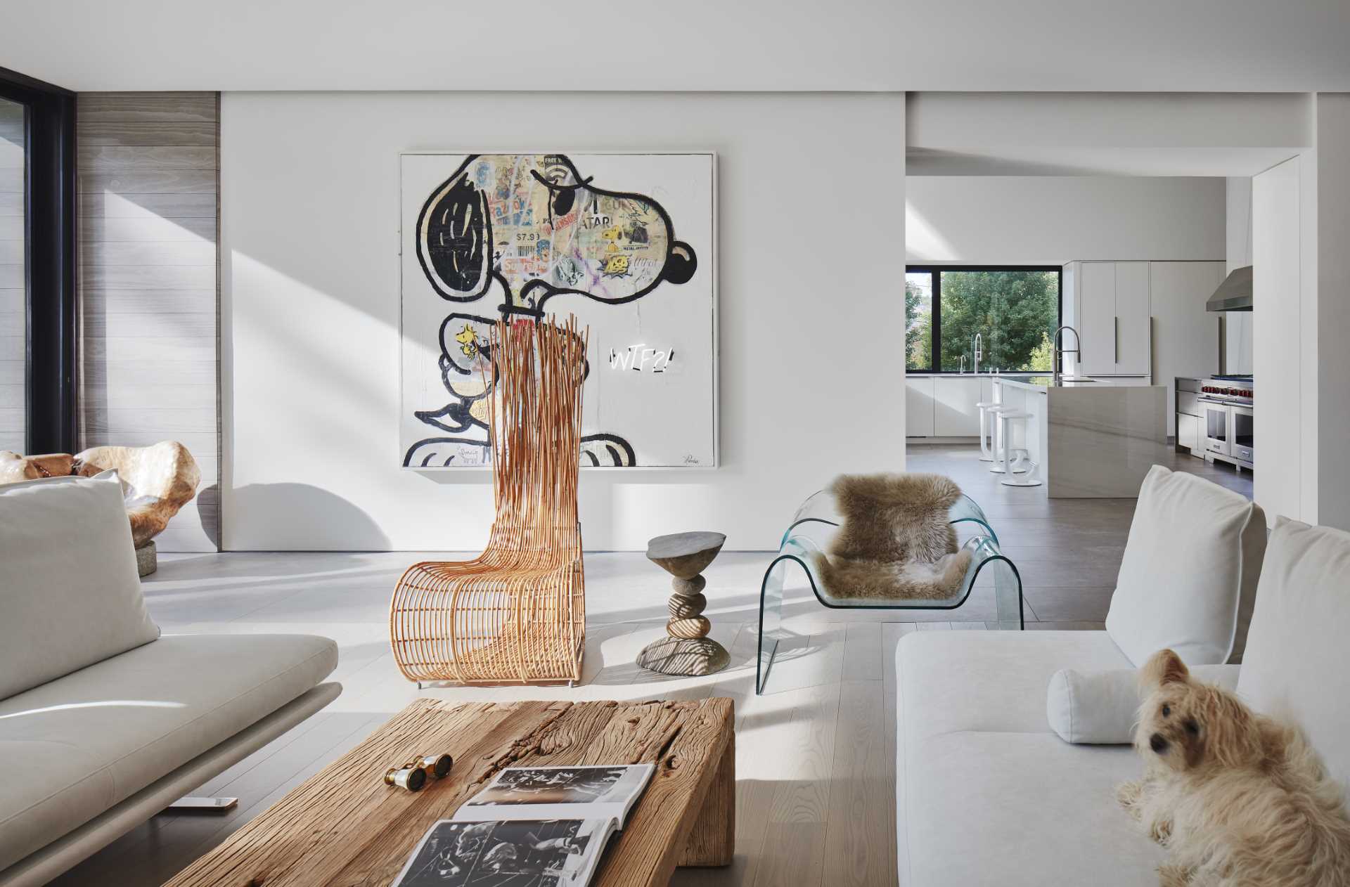 An opening by the living room that leads to the kitchen with white cabinets and an island.