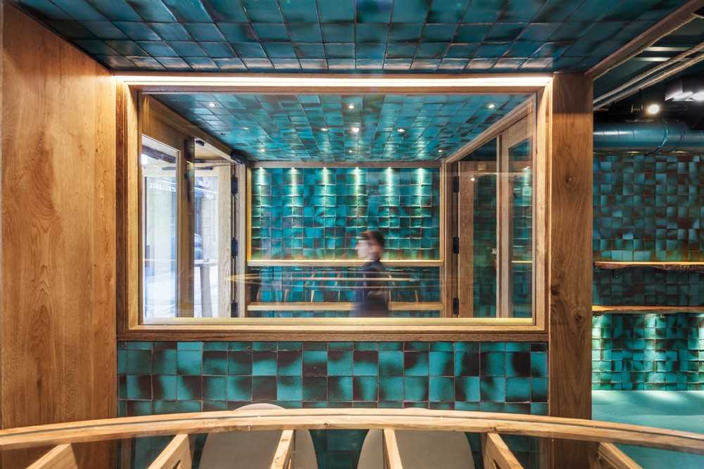 Stepping inside this restaurant, you're immediately surrounded by handmade ceramic tiles, designed specifically for the project as a way of introducing an aquatic effect through its intense turquoise color, its imperfections, and its brightness.