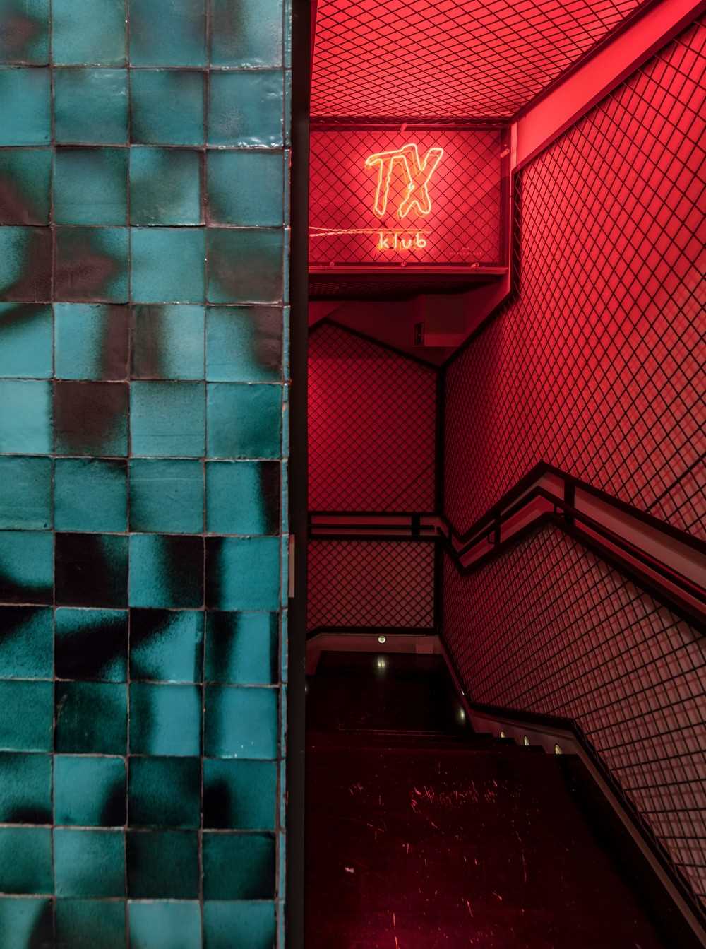 A narrow and mysterious tunnel lined with red light attracts customers to the basement, where a private club is located.