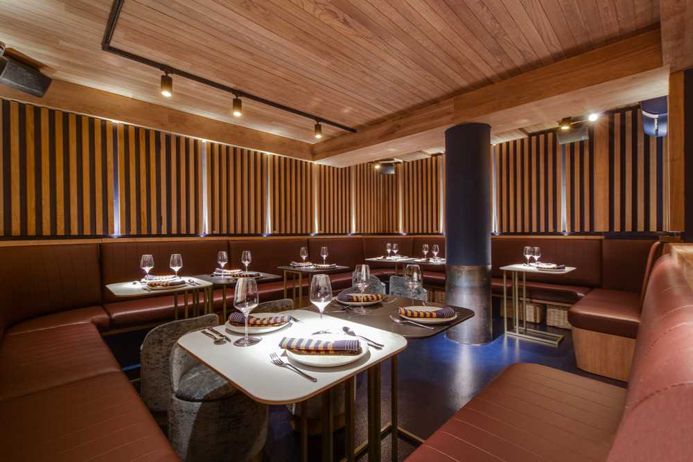 The design of this restaurant basement was inspired by an old boat cellar where the warm golden wood-tones surround the customers, in contrast to the blue maritime floor.