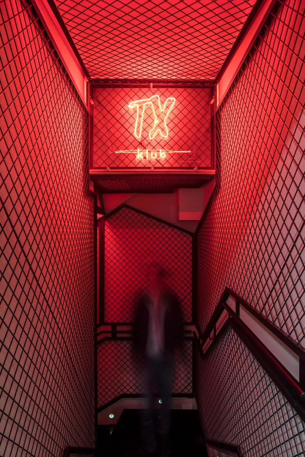 A narrow and mysterious tunnel lined with red light attracts customers to the basement, where a private club is located.