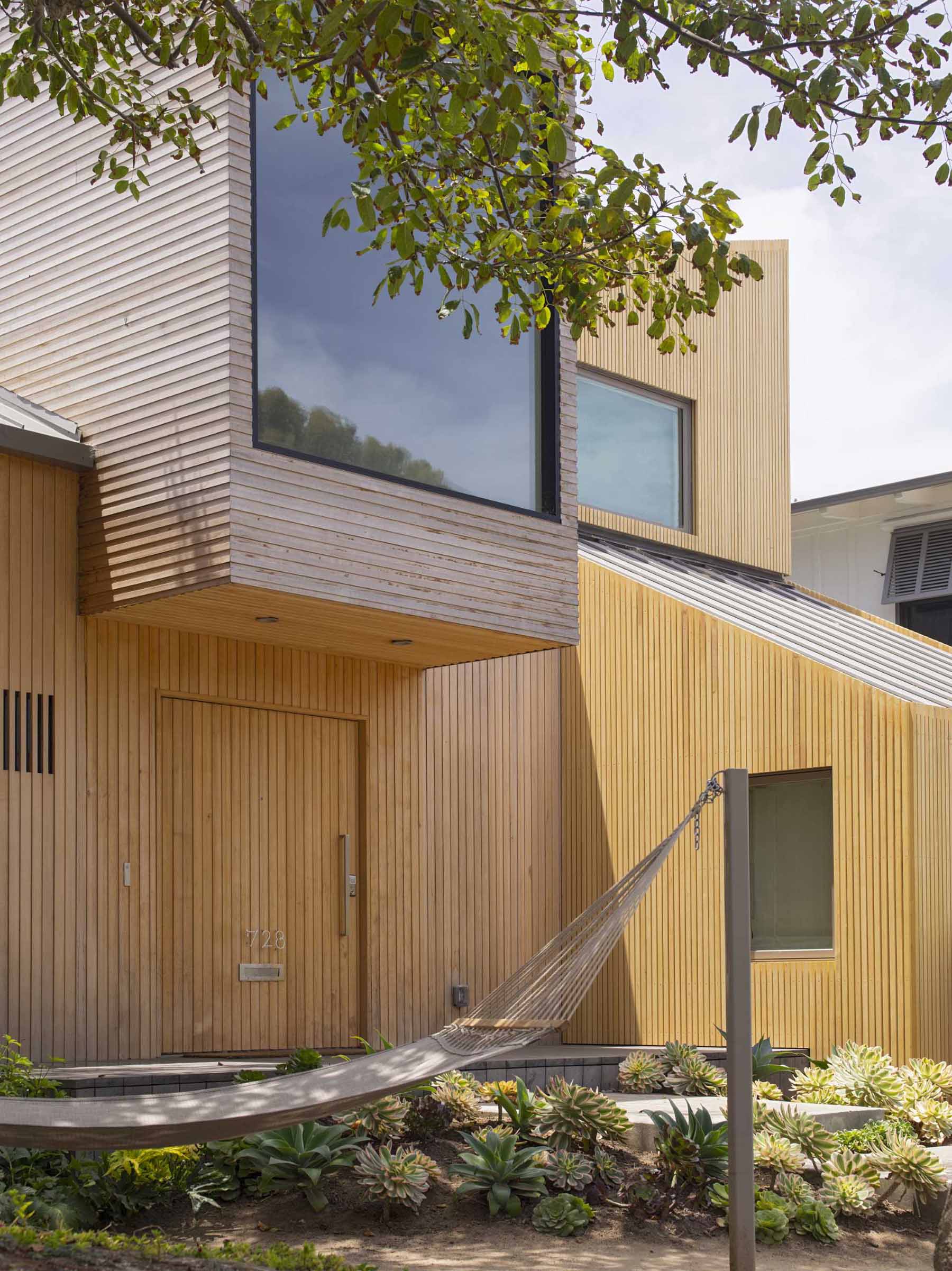 The front door is seamlessly integrated into the exterior of this modern home, with a protruding section of the home providing shelter for the door. 