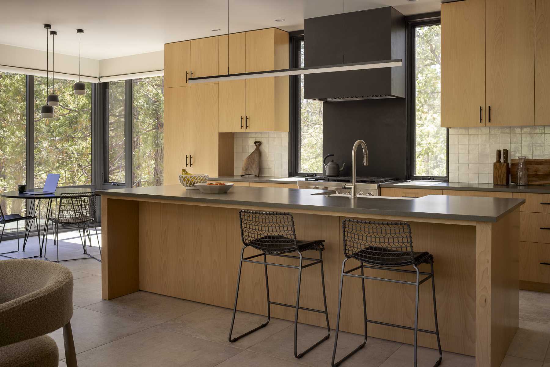 A small dining area by the windows shares the open floor plan with the kitchen, which showcases Beech Veneer cabinets and grey quartz countertops.