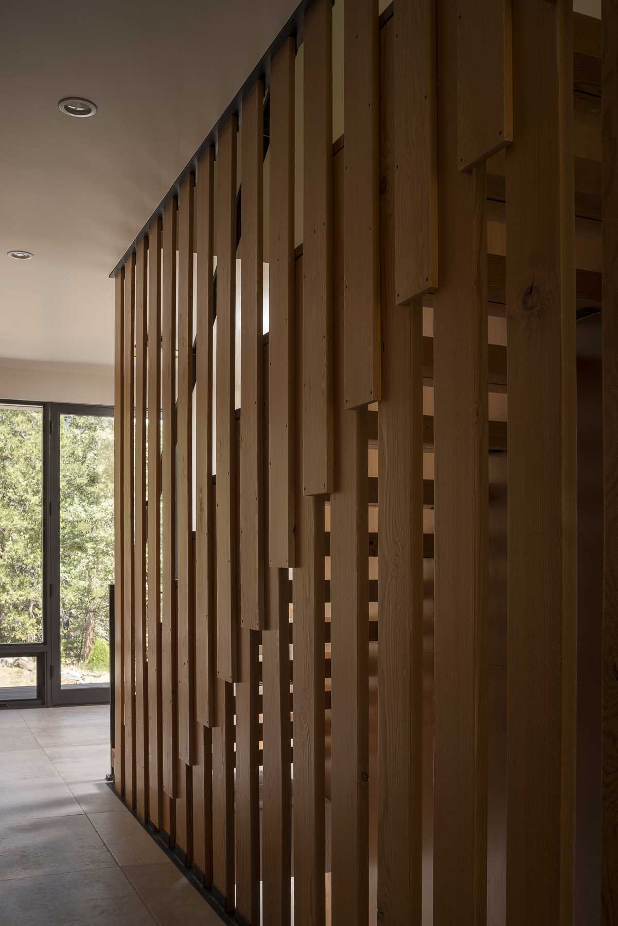 The main floor stair treads are fa،oned from thick pieces of reclaimed fir and give the impression of a floating staircase; ،wever, they are cleverly supported by a series of overlapping slats that ec، the vertical layout of the exterior siding and the surrounding trees.