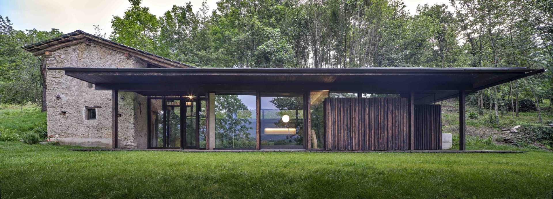 An abandoned stone ruin that was once overgrown with brambles, has been transformed into a small off-grid home with burnt larch wood and large windows.