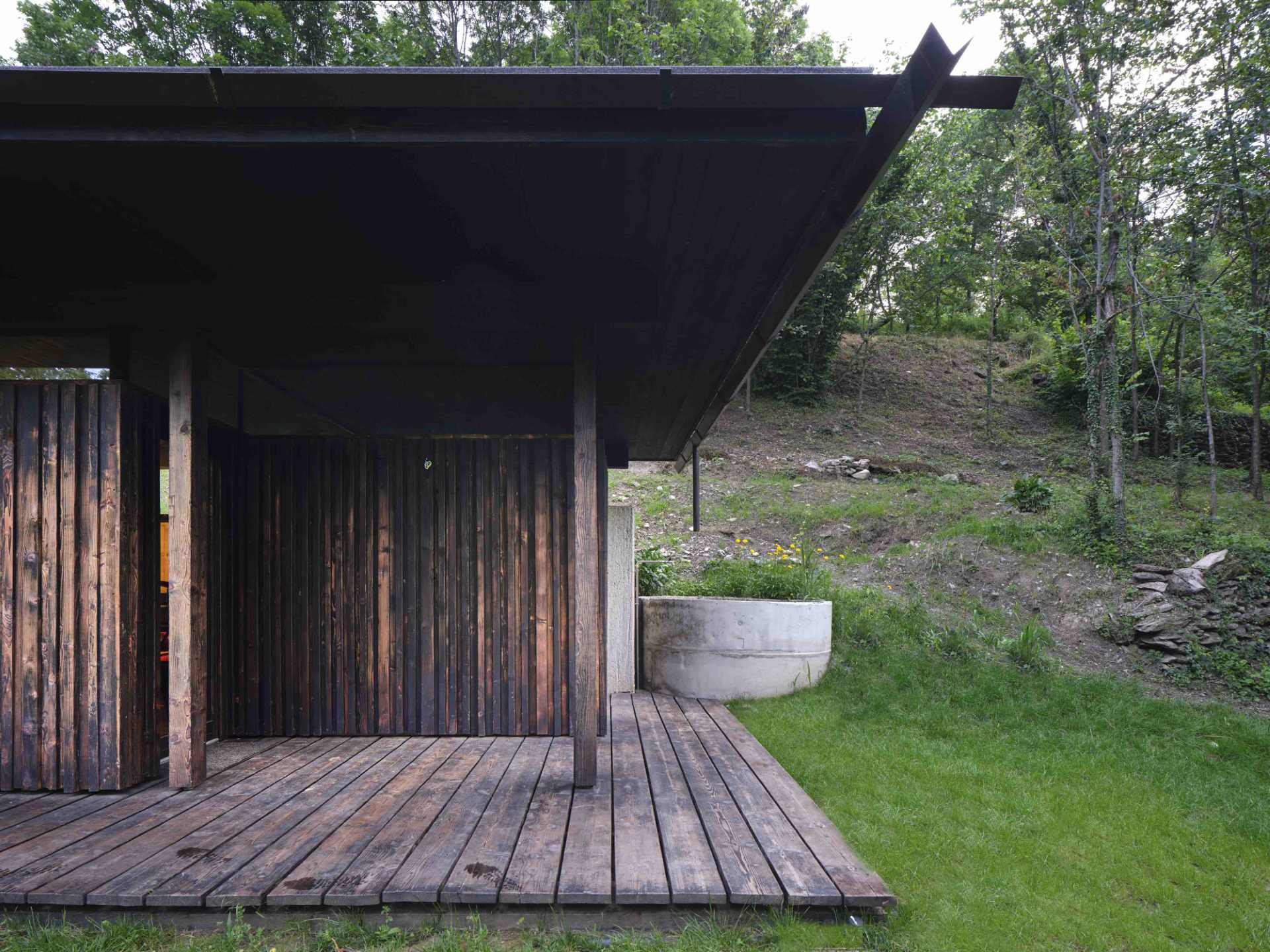 An abandoned stone ruin that was once overgrown with brambles, has been transformed into a small off-grid home with burnt larch wood and large windows.