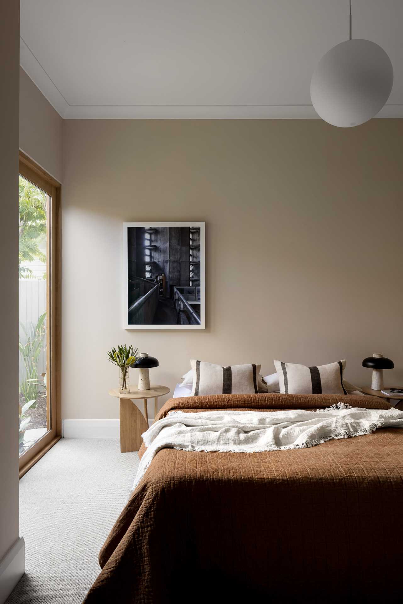In this bedroom, which has a view of the garden, warm neutral colors have been used to create a cozy vibe.
