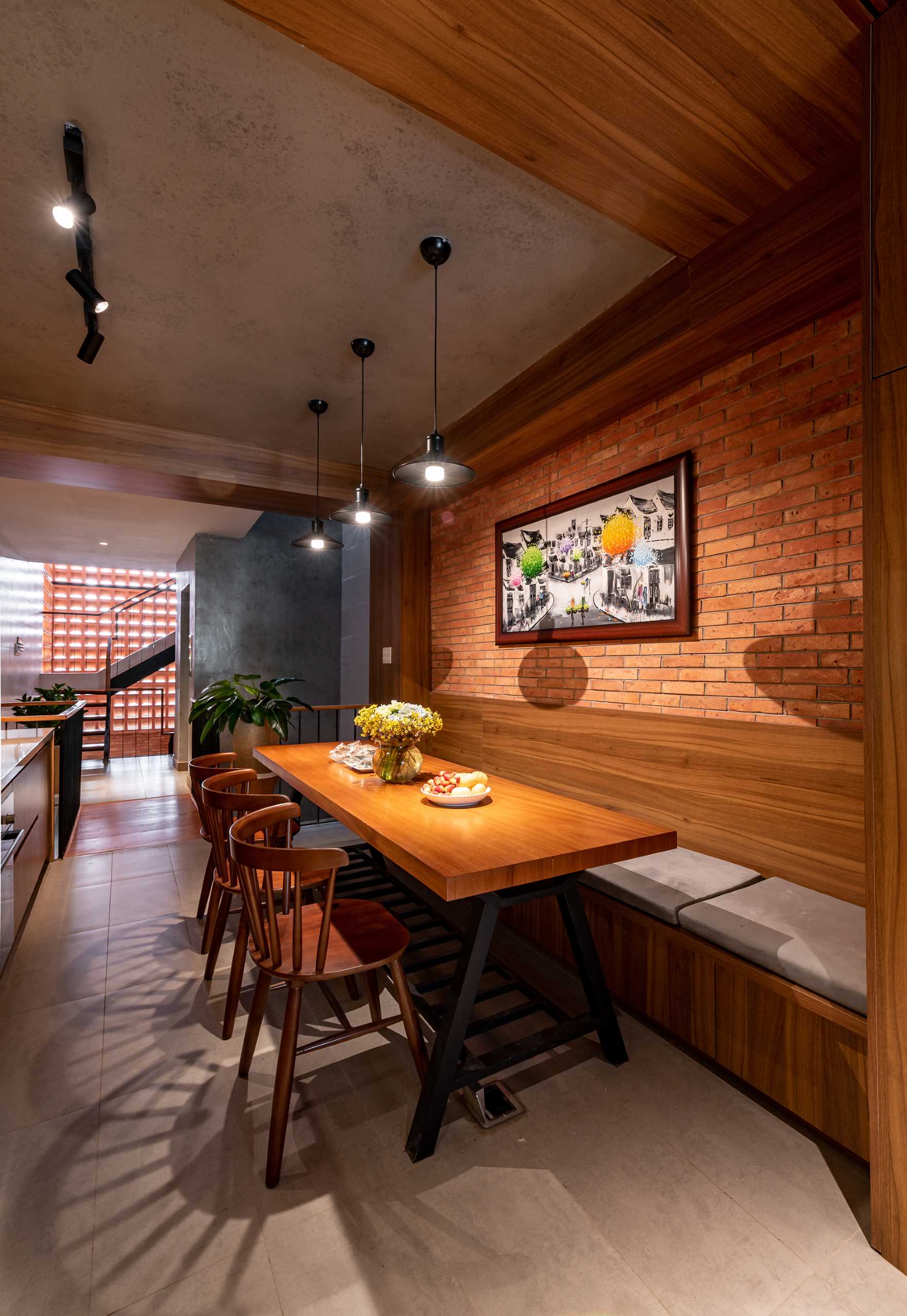The dining area includes built-in banquette seating, while three pendant lights highlight the wood table.