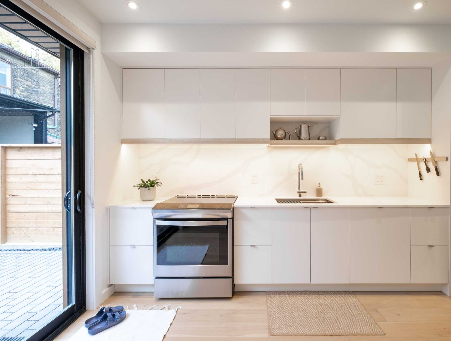 A small laneway house with a modern kitchen that includes lighting beneath the cabinets.
