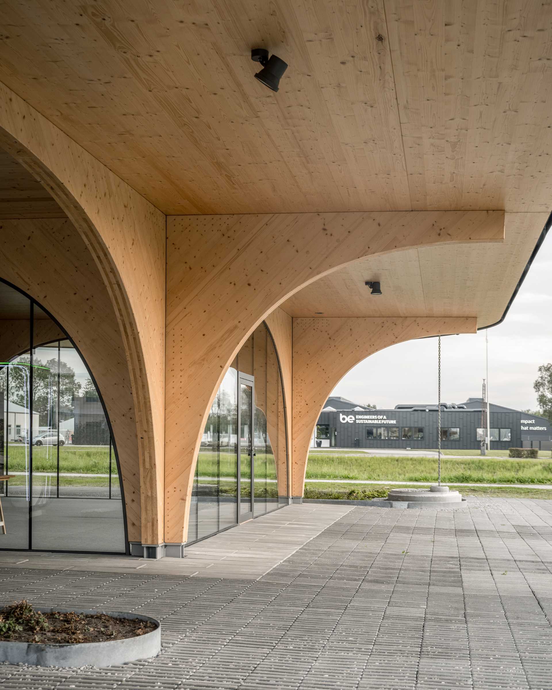 A contemporary charging park features an exposed wood structure and a park with native plants.
