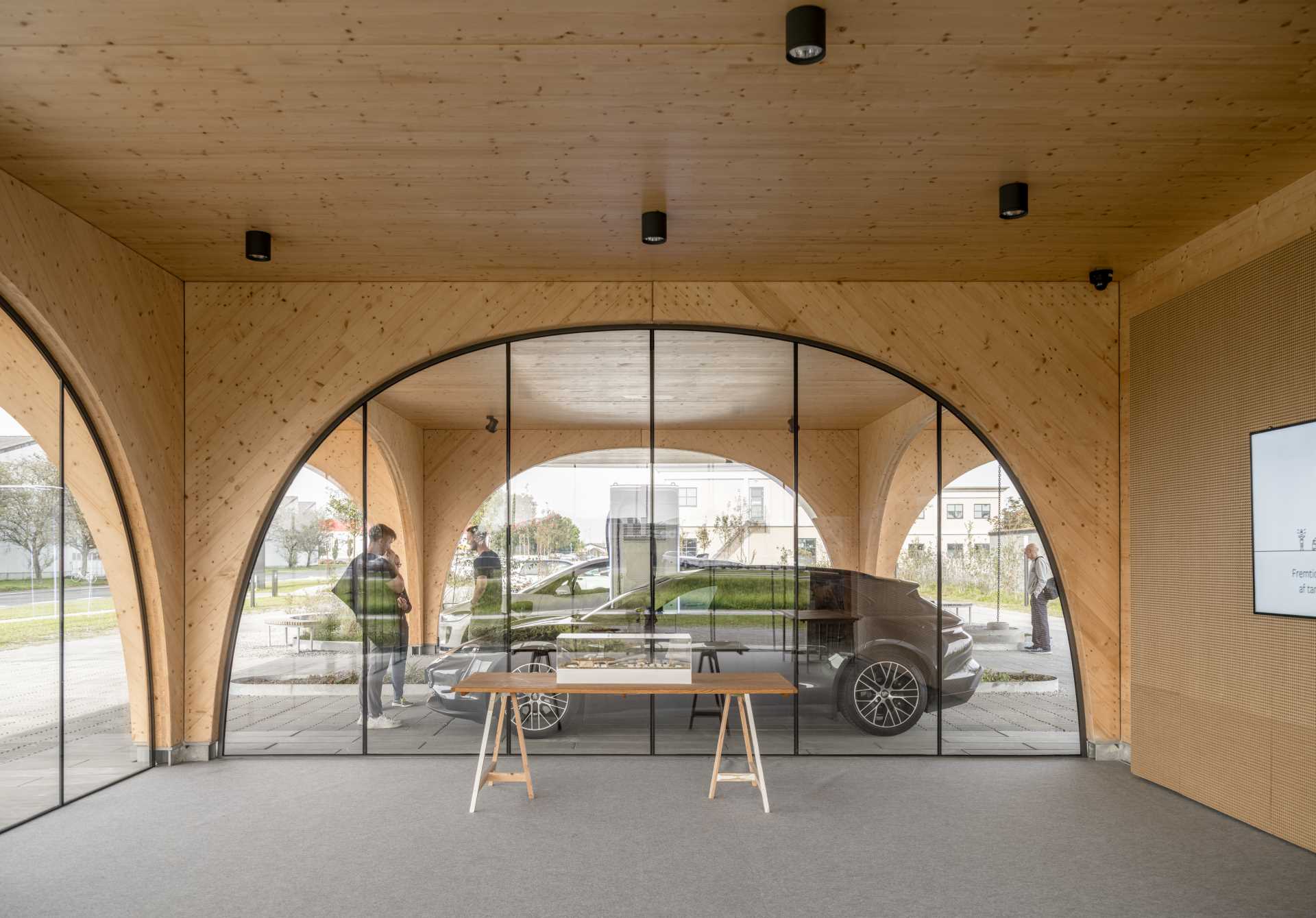 A contemporary charging park features an exposed wood structure and a park with native plants.