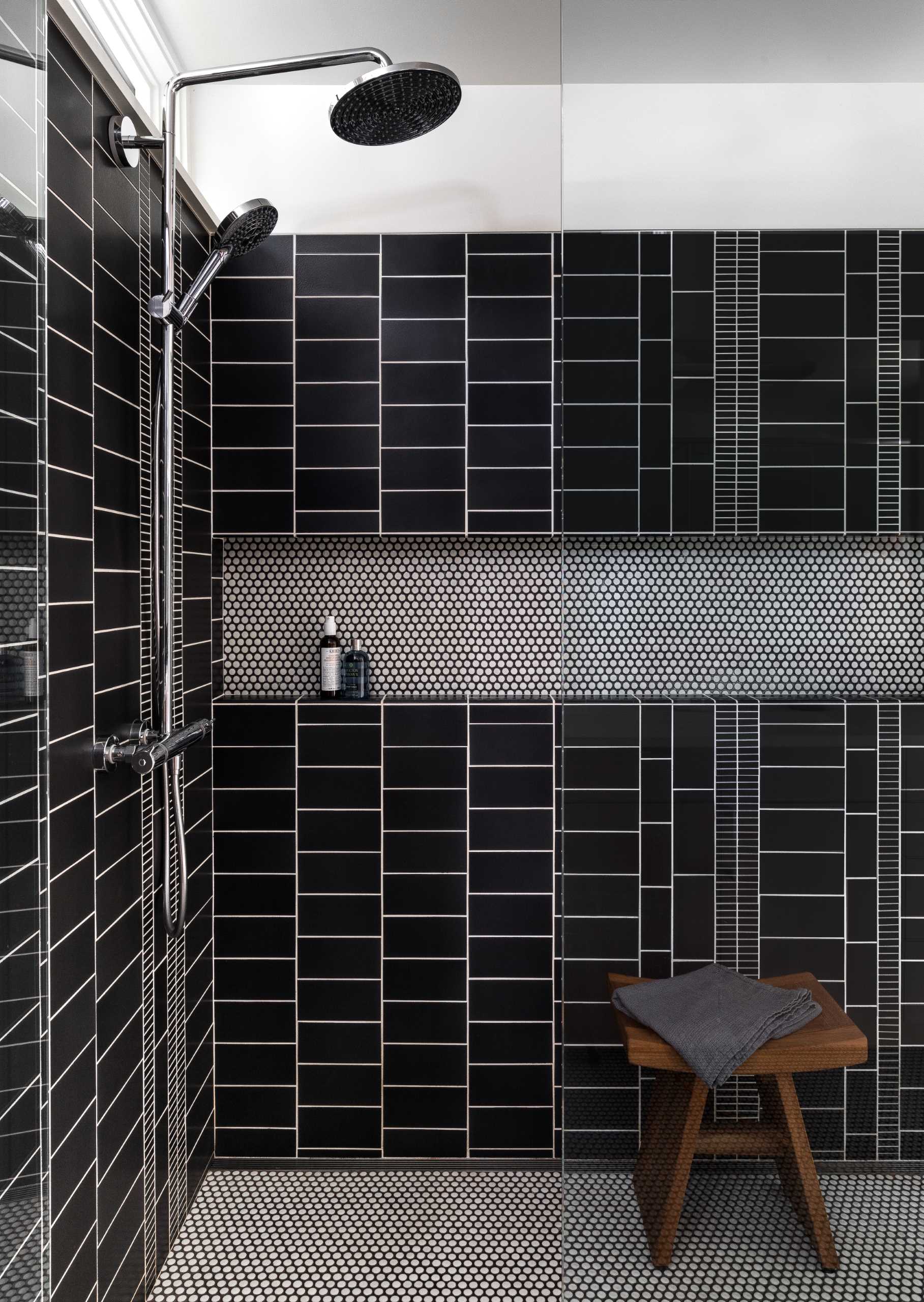 In this modern bathroom, black and white tiles have been c،sen to line the s،wer, with contrasting grout allowing each tile shape to stand out.