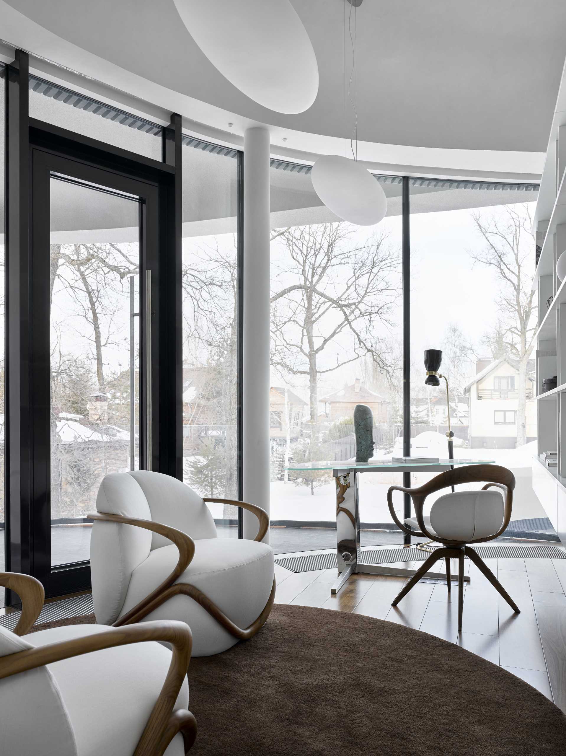 In a home office, a door in the curved glass wall opens to a balcony.