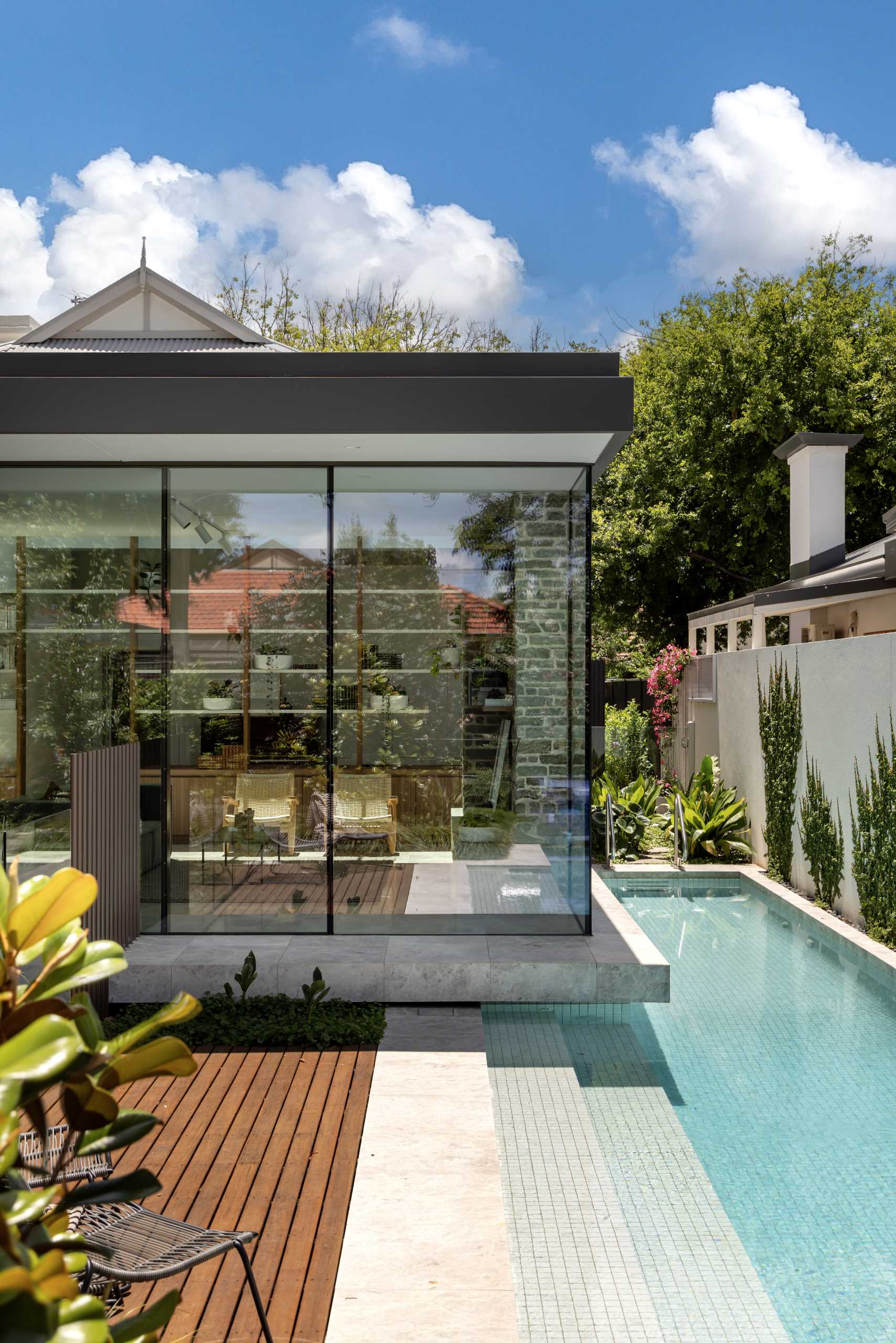 A structured floating box with glass walls has a nearby sunken garden, a patio, and a rectangular pool.