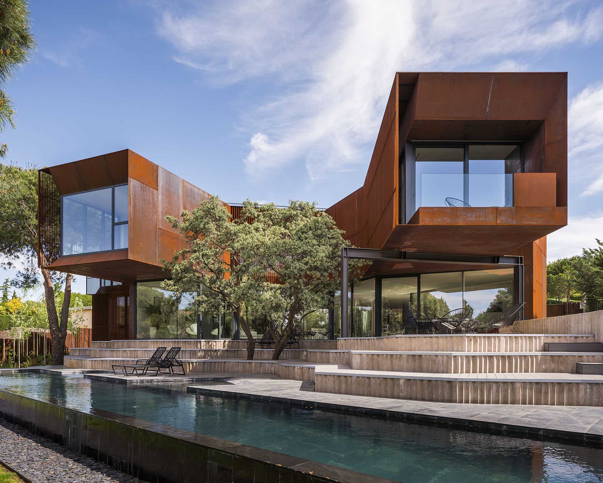 A modern house features large windows and a weathered steel facade.