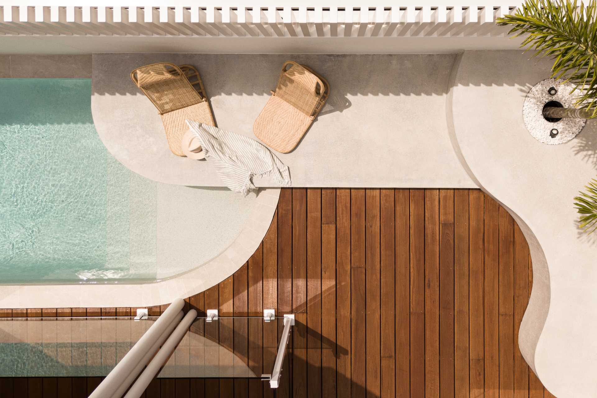 A swimming pool with a wood deck and a raised platform for lounging in the sun.