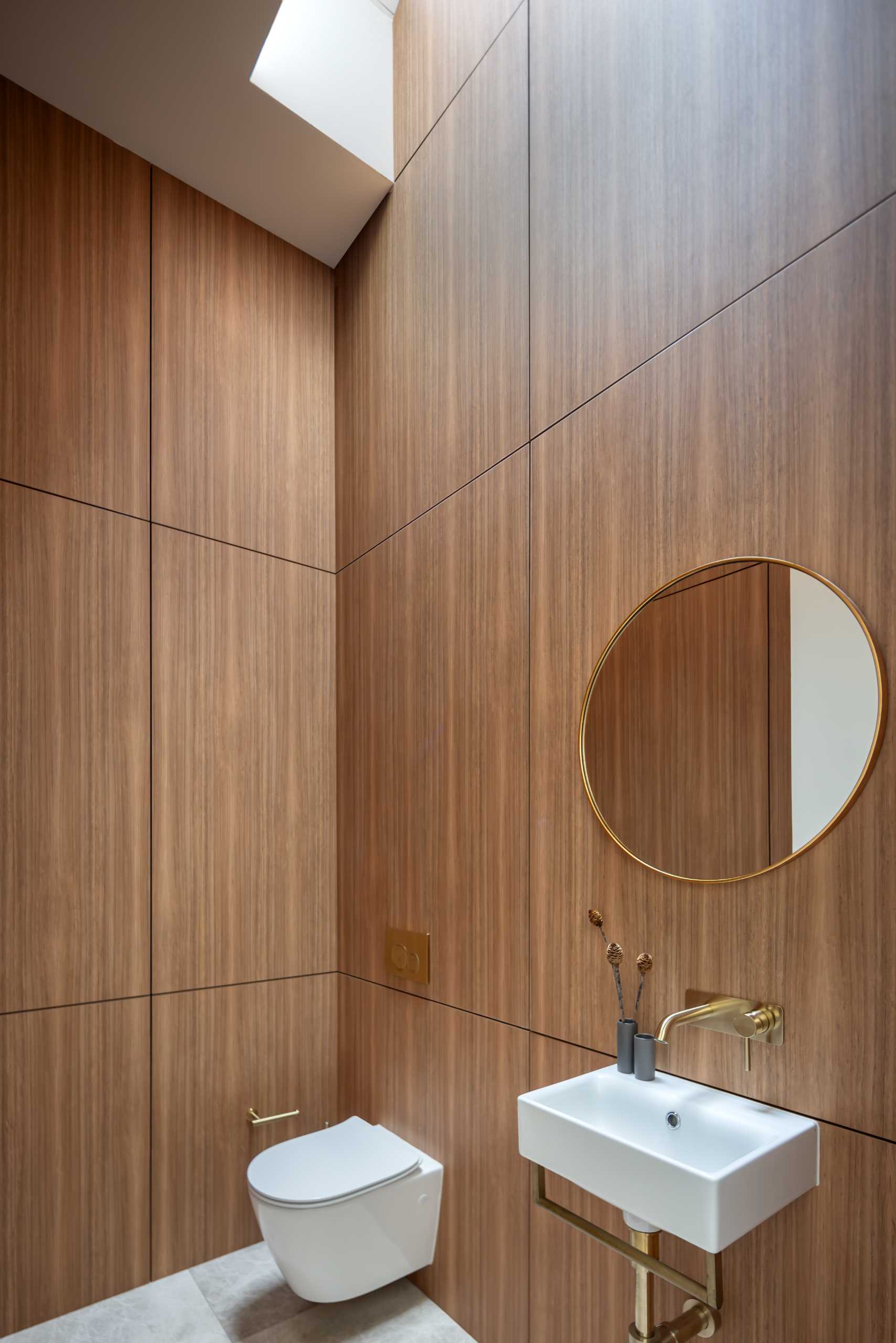 In a powder room, floor-to-ceiling wood walls are highlighted by the skylight.