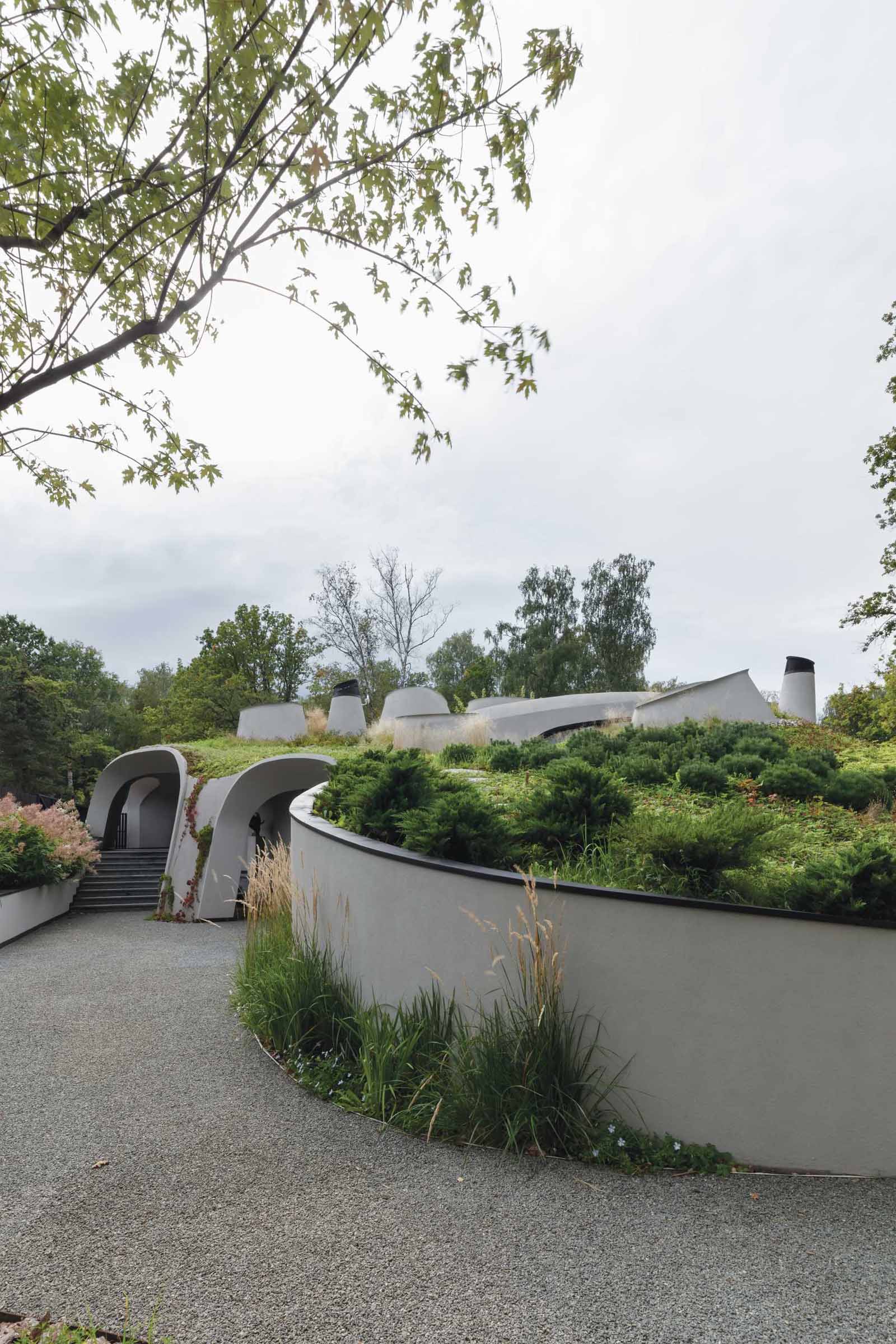 A modern sculptural home with curves that's been built into an artificially created landscape.