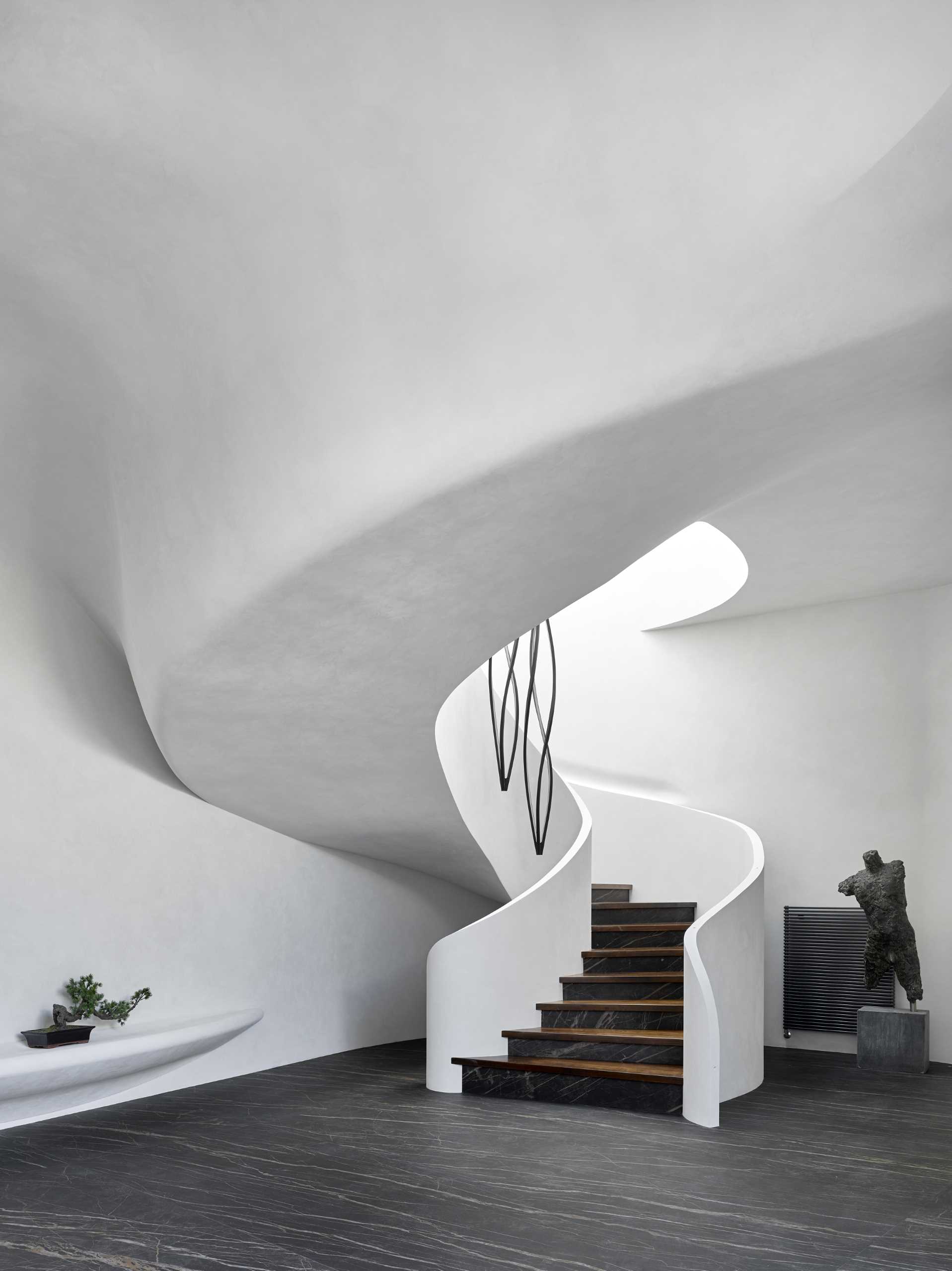Spiral stairs built into the design of this modern home add an interior sculptural element, while the walls contrast the dark floor.