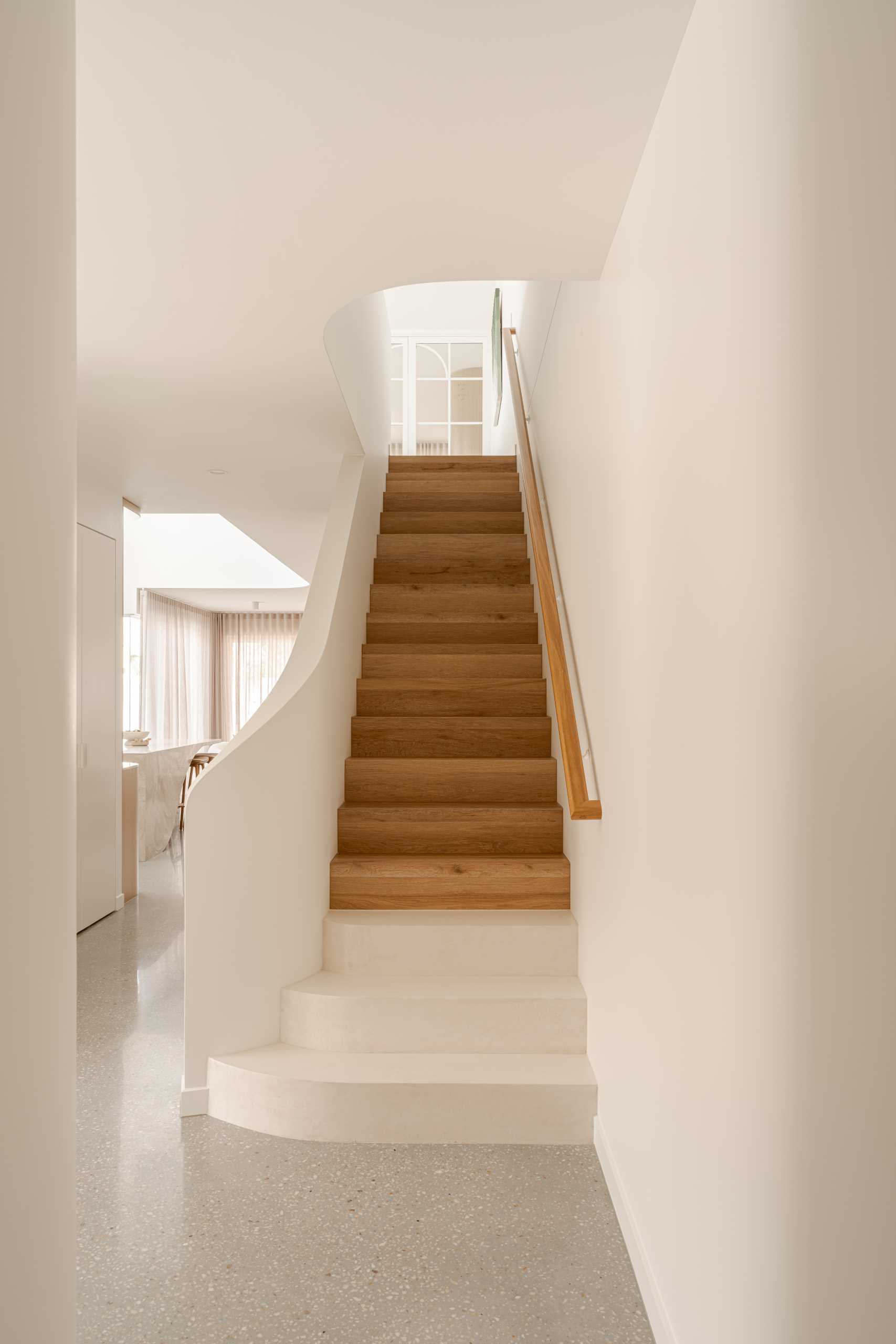 Wood stairs lead to the upper floor of this contemporary home with a neutral color palette.