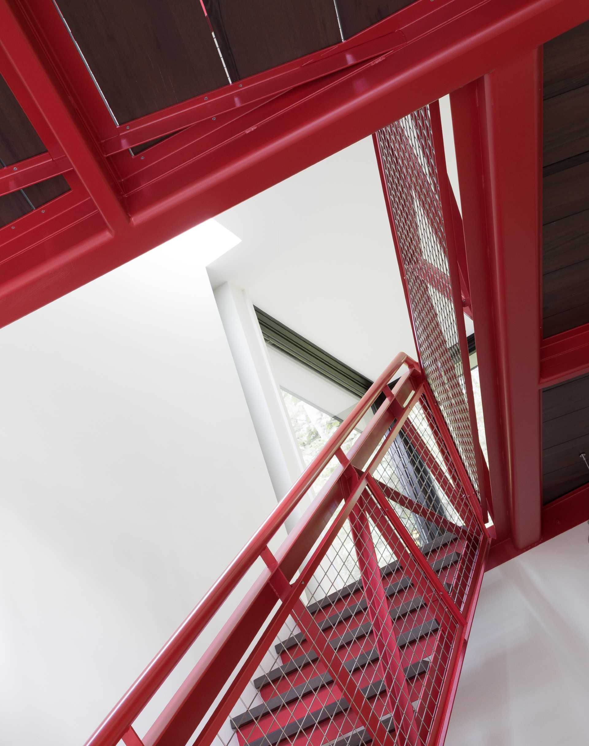 A red metal staircase designed by DeForest, connects the main living level of the home with the upper level.