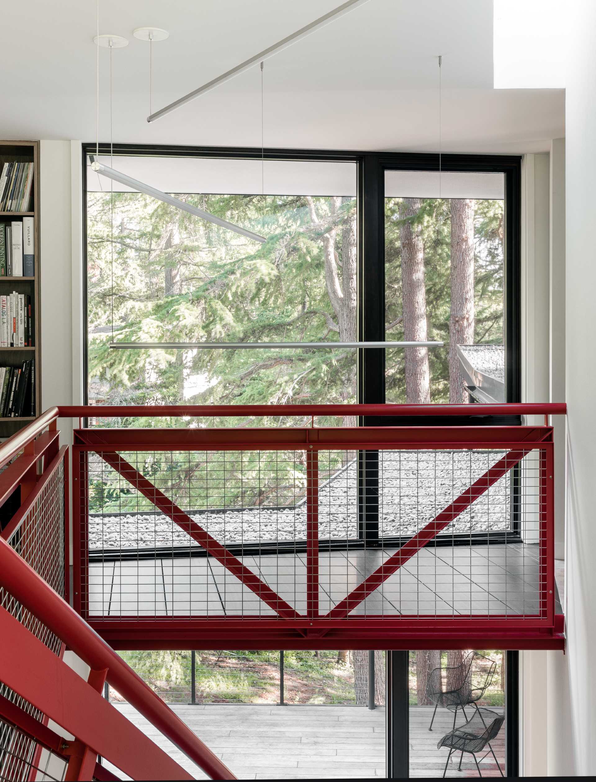 A red metal staircase designed by DeForest, connects the main living level of the ،me with the upper level.