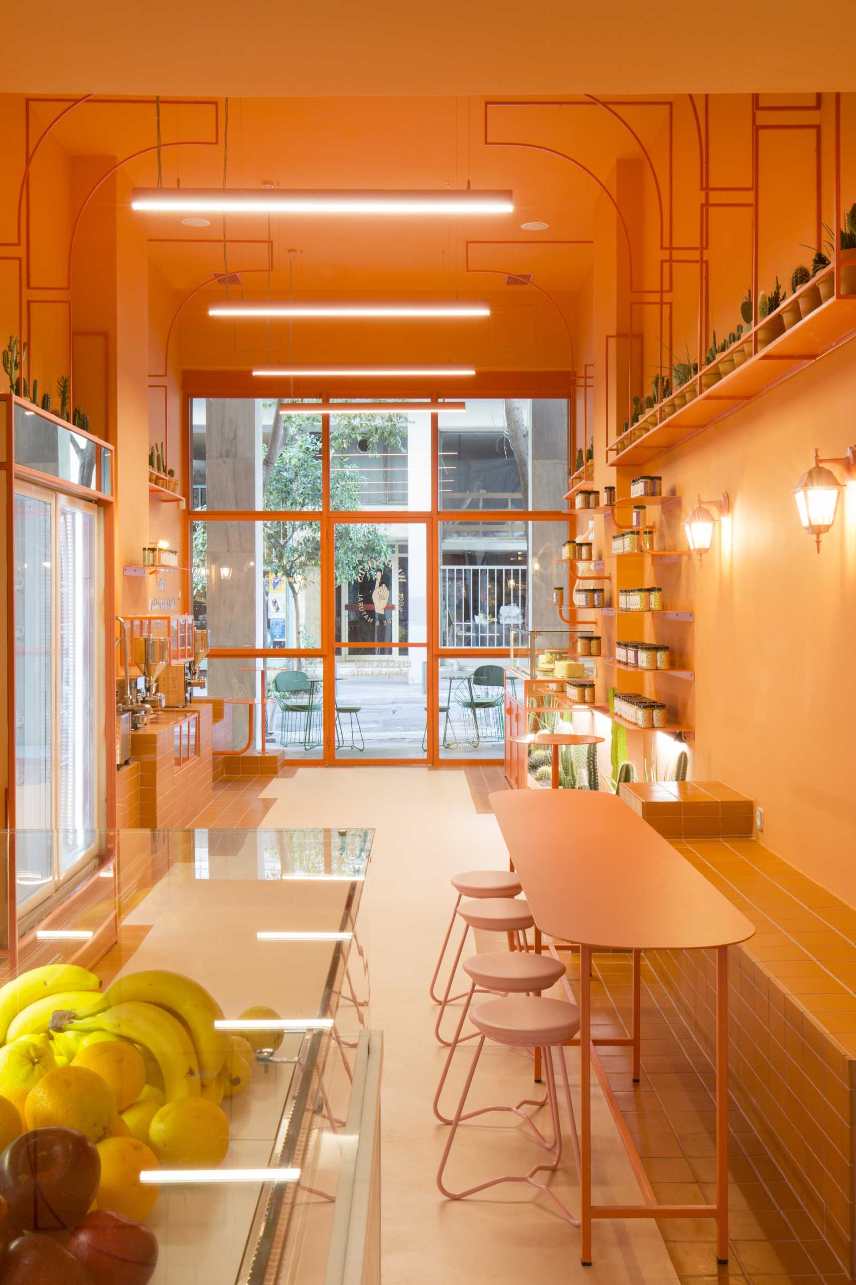 A modern retail store with a monochromatic terracotta interior that also includes built-in planters for cacti.