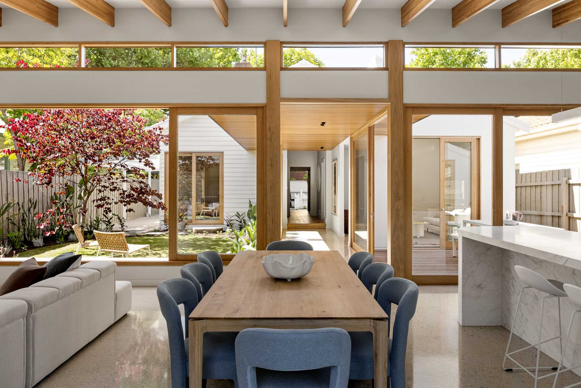 The dining area separates the living room from the kitchen, and includes a wood table surrounded by upholstered chairs.