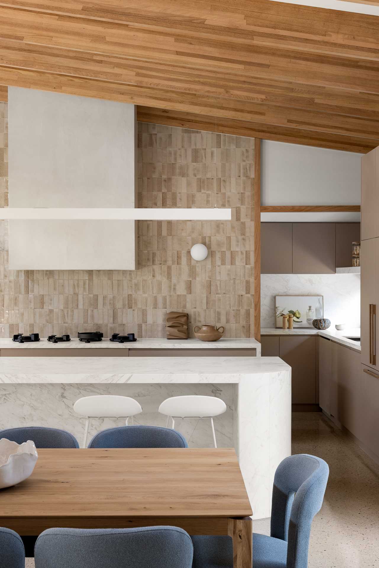 The kitchen has a neutral palette and an island, while tucked behind it is a walk-through laundry and pantry.