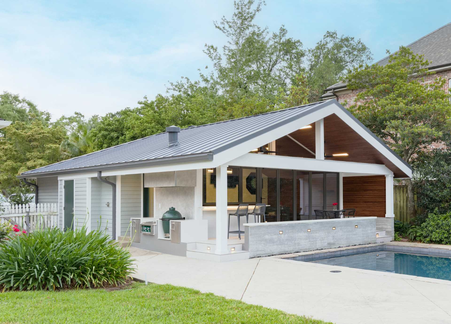 A garage was transformed into a modern pool house with a bar and covered seating.