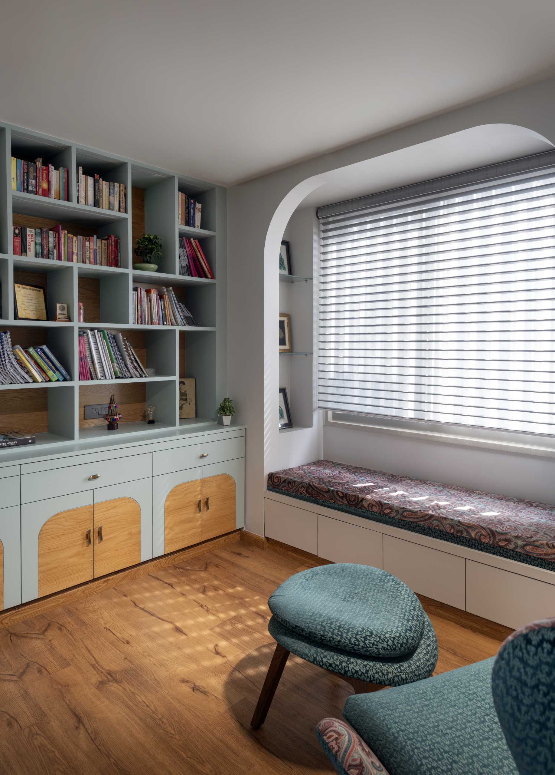 A contemporary study with built-in shelves and cabinets, and a window seat.