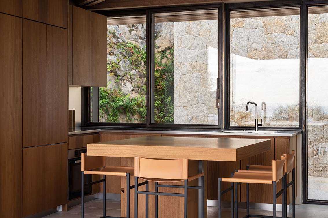 The kitchen is located off the dining room and through an opening in the stone wall. The warm wood cabinets complement the kitchen island, which has an overhang for seating.