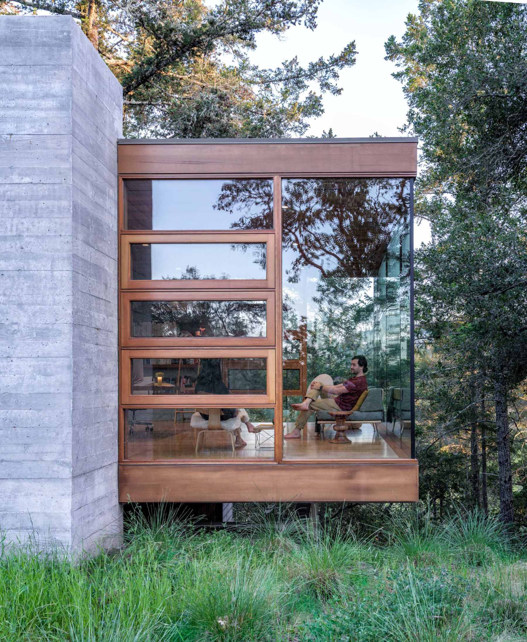A wood-framed glass box is home to a backyard office.