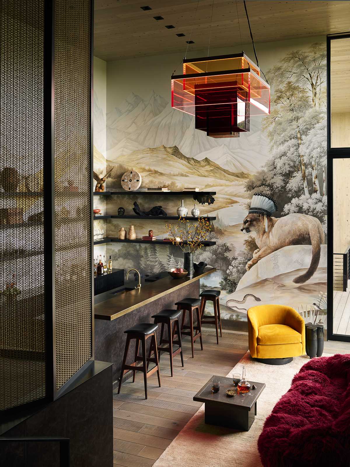 A bar and lounge features a hand-painted wallpaper mural from Aqualille, while the furnishings include open shelving and a custom sculptural chandelier by Johanna Grawunder.