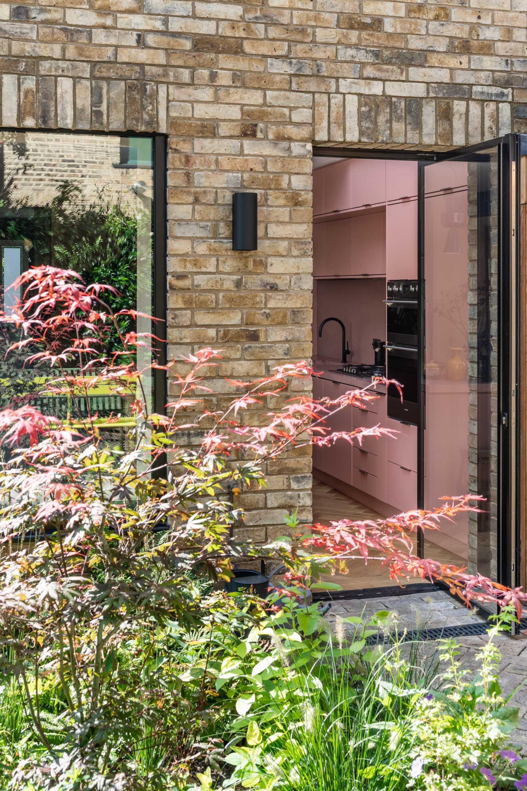 A brick home extension with a blush pink kitchen and window seats.