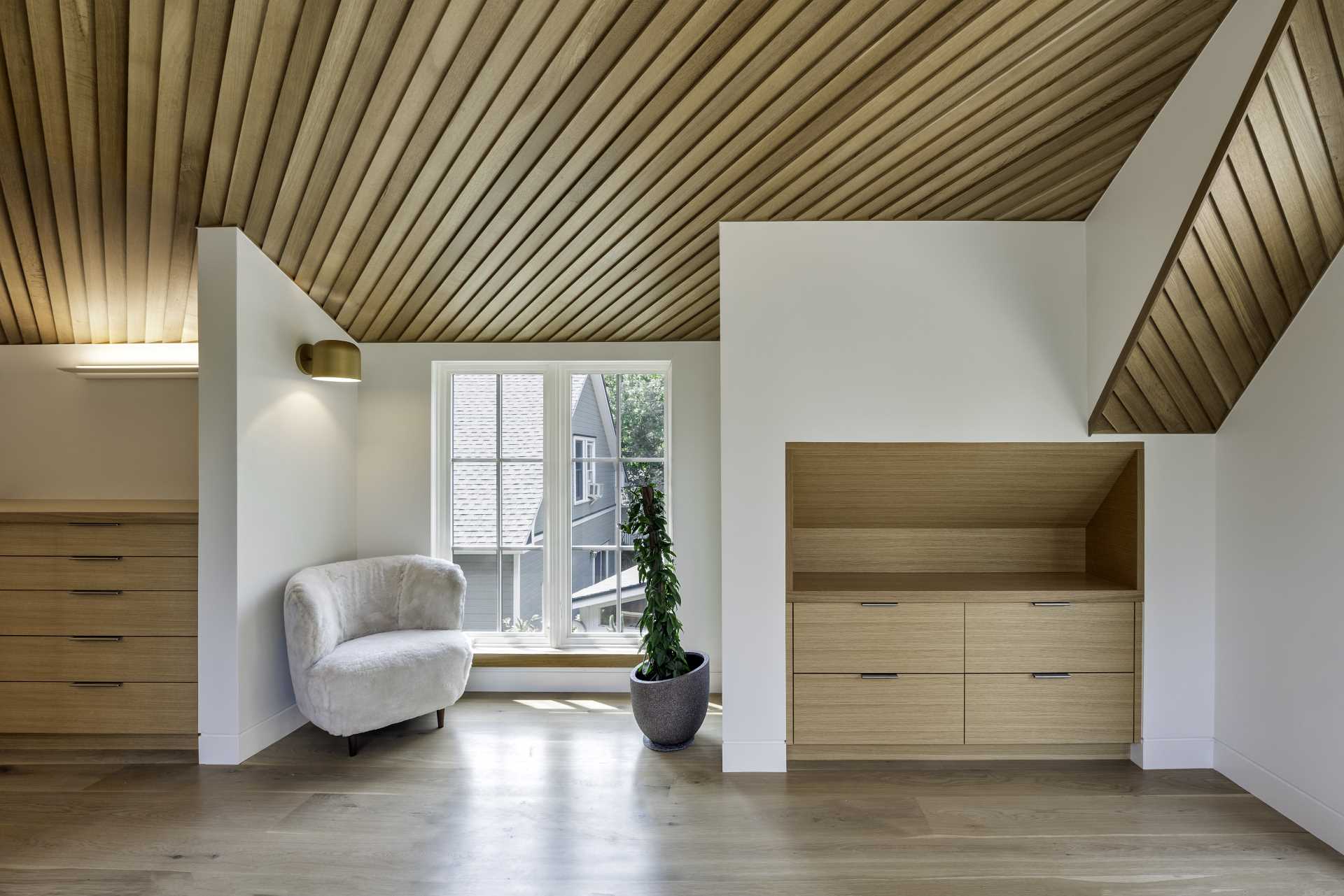 In this main bedroom, the ceiling is composed of lap siding installed at an angle, aligned perfectly at the ridge, while built-in dressers make smart use of the available ،e.