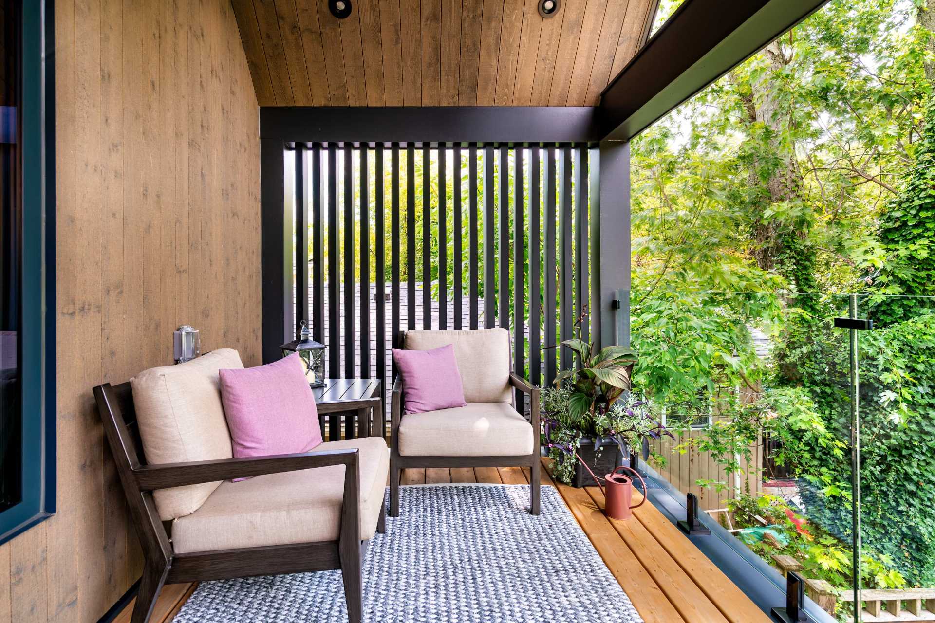 A modern home with a covered balcony that provides views of the trees.