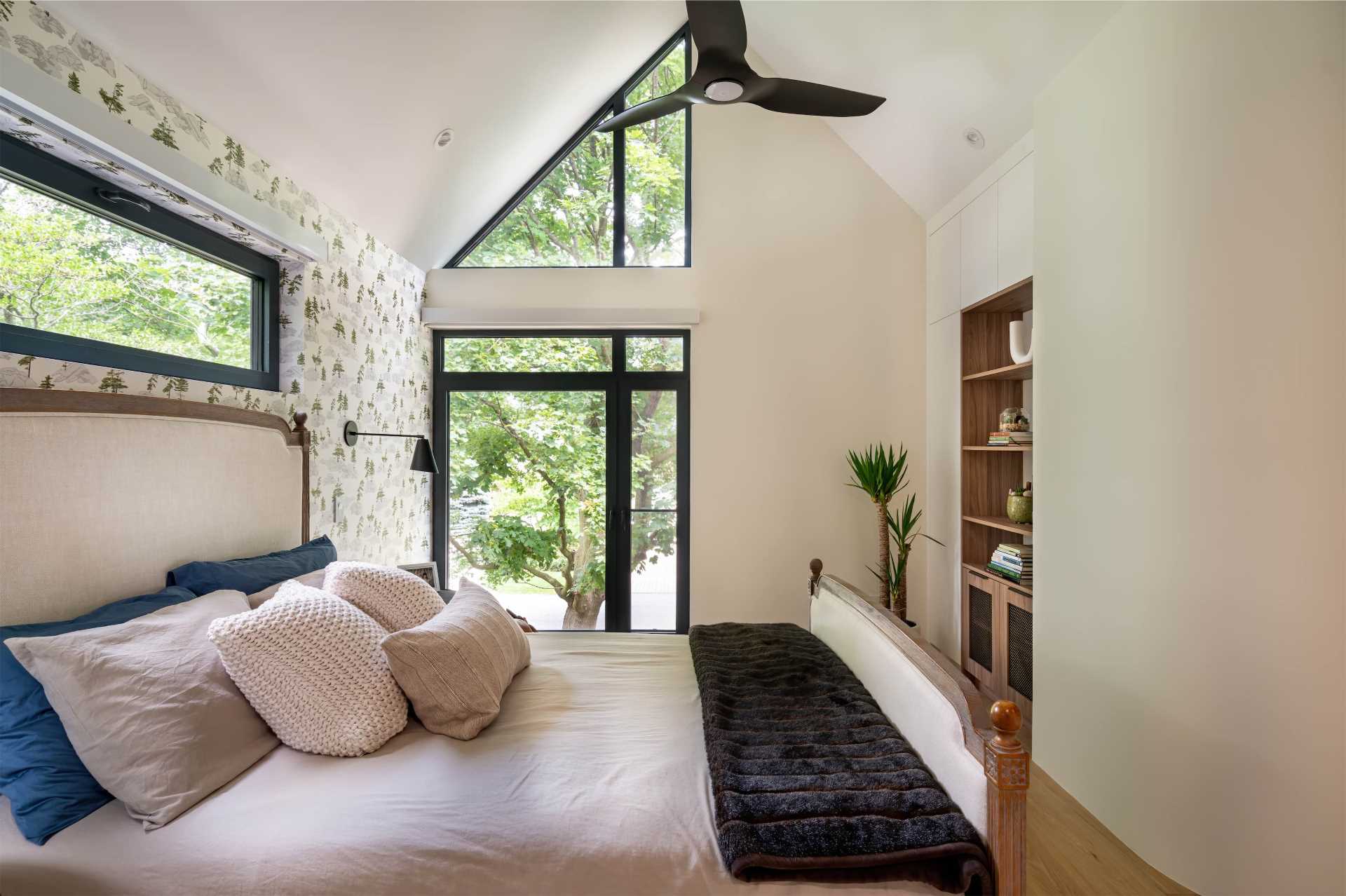 A modern bedroom with an angled window and built-in furniture.