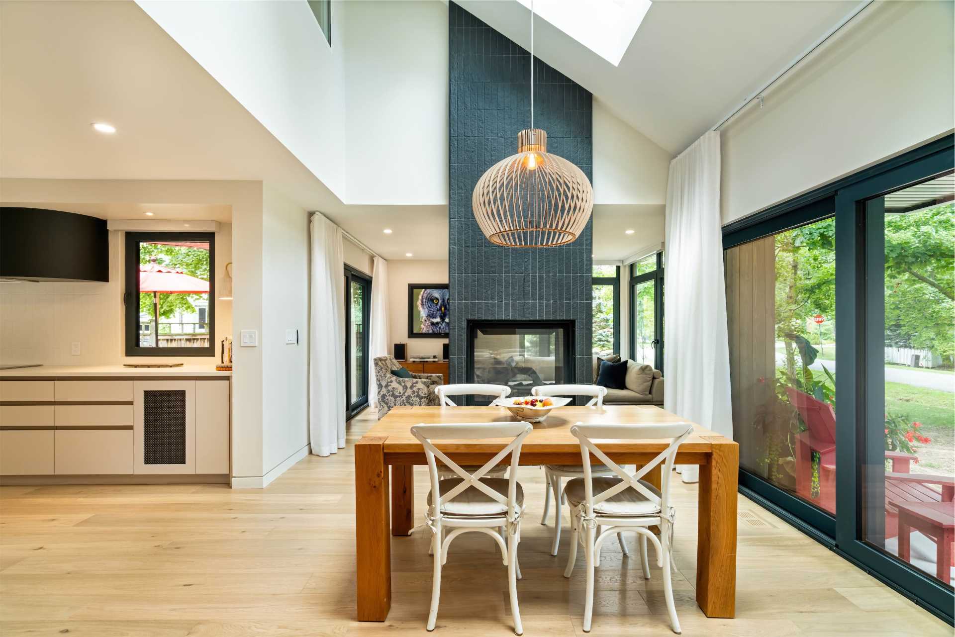 An updated and reimagined double-sided fireplace clad in tiles unifies separate living and dining areas.