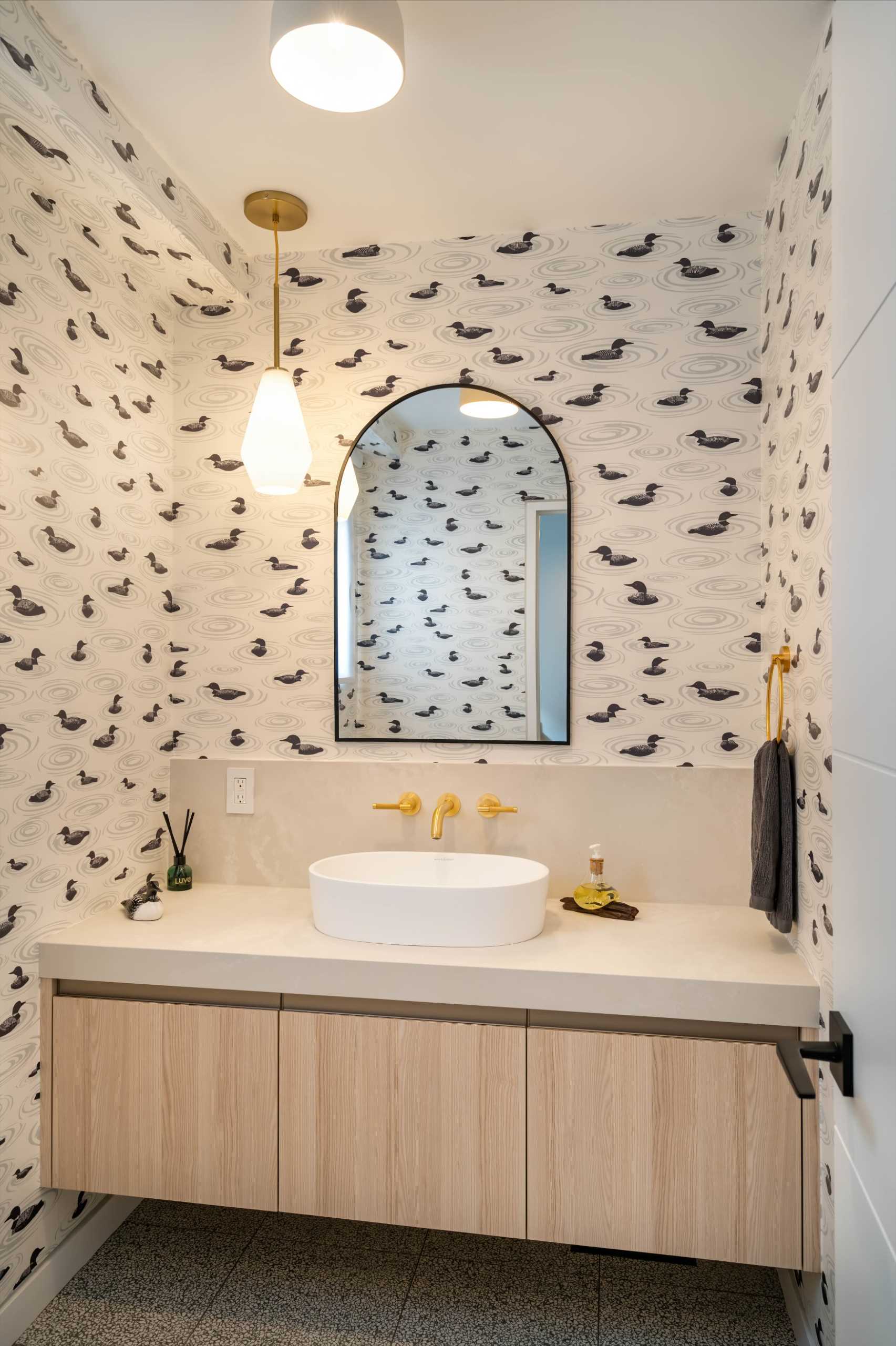A modern powder room that features wallpaper with a duck print.