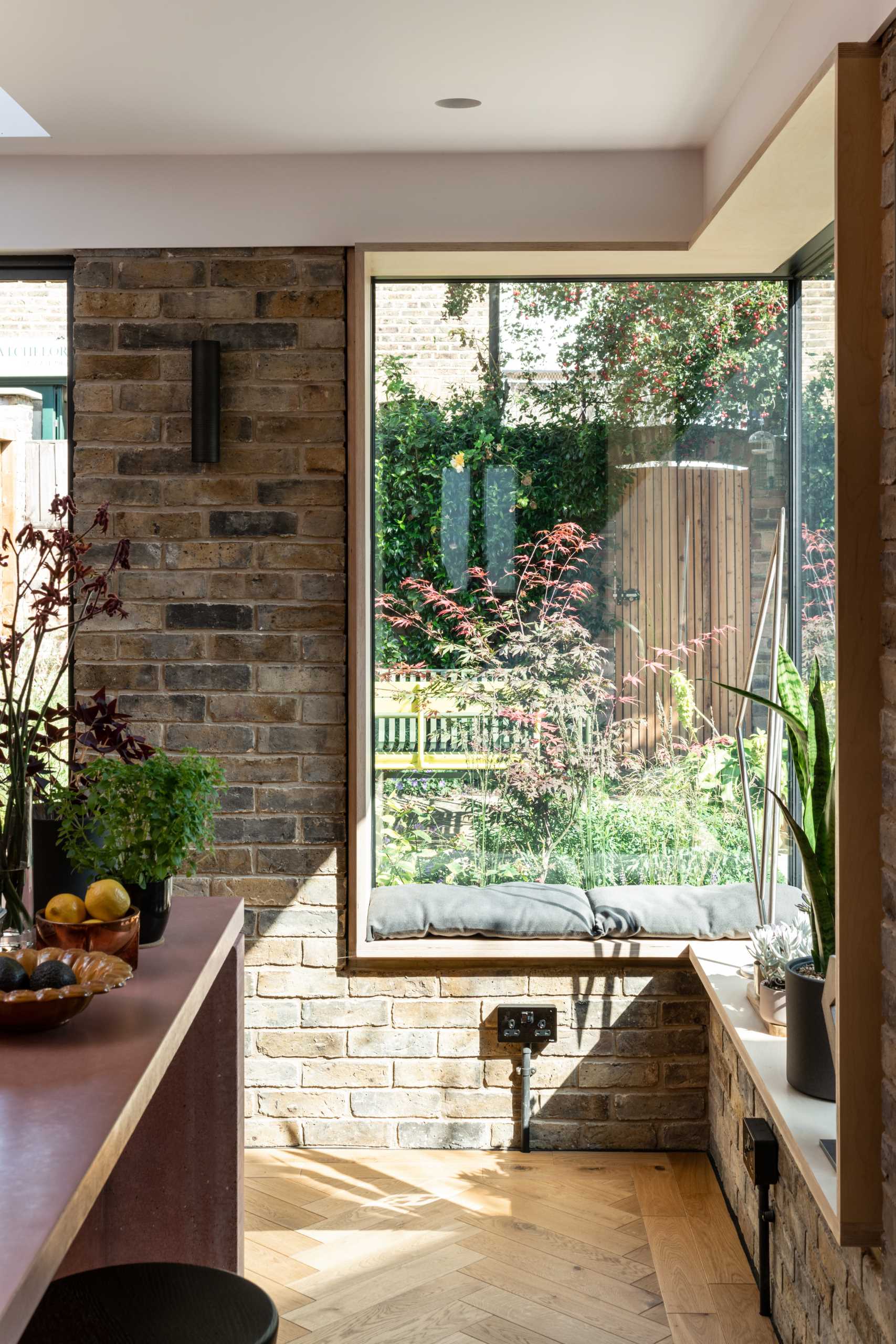 A brick home extension with a blush pink kitchen and window seats.