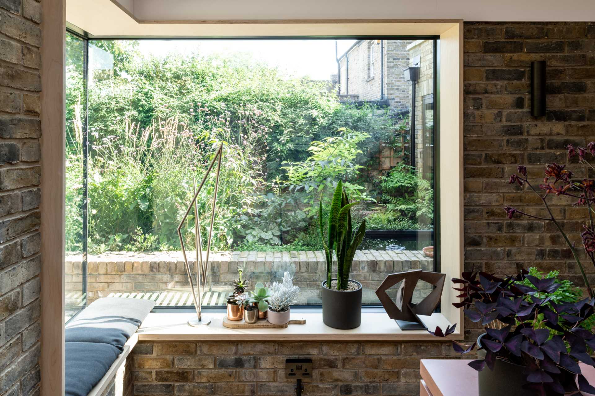 A brick home extension with a blush pink kitchen and window seats.