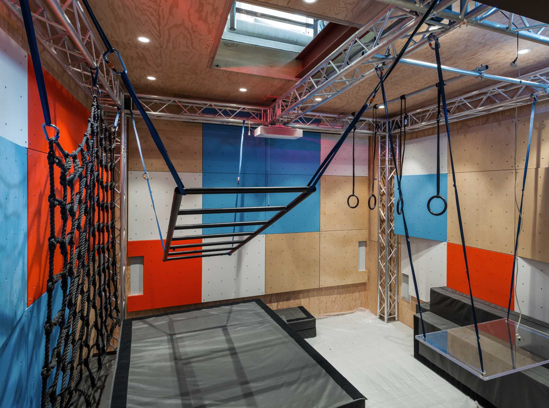 A home with a Ninja Room, which features climbing walls and spaceframes, hammocks, swings, and ropes. A ‘floor window’ in the living room peeks into the ninja room below.