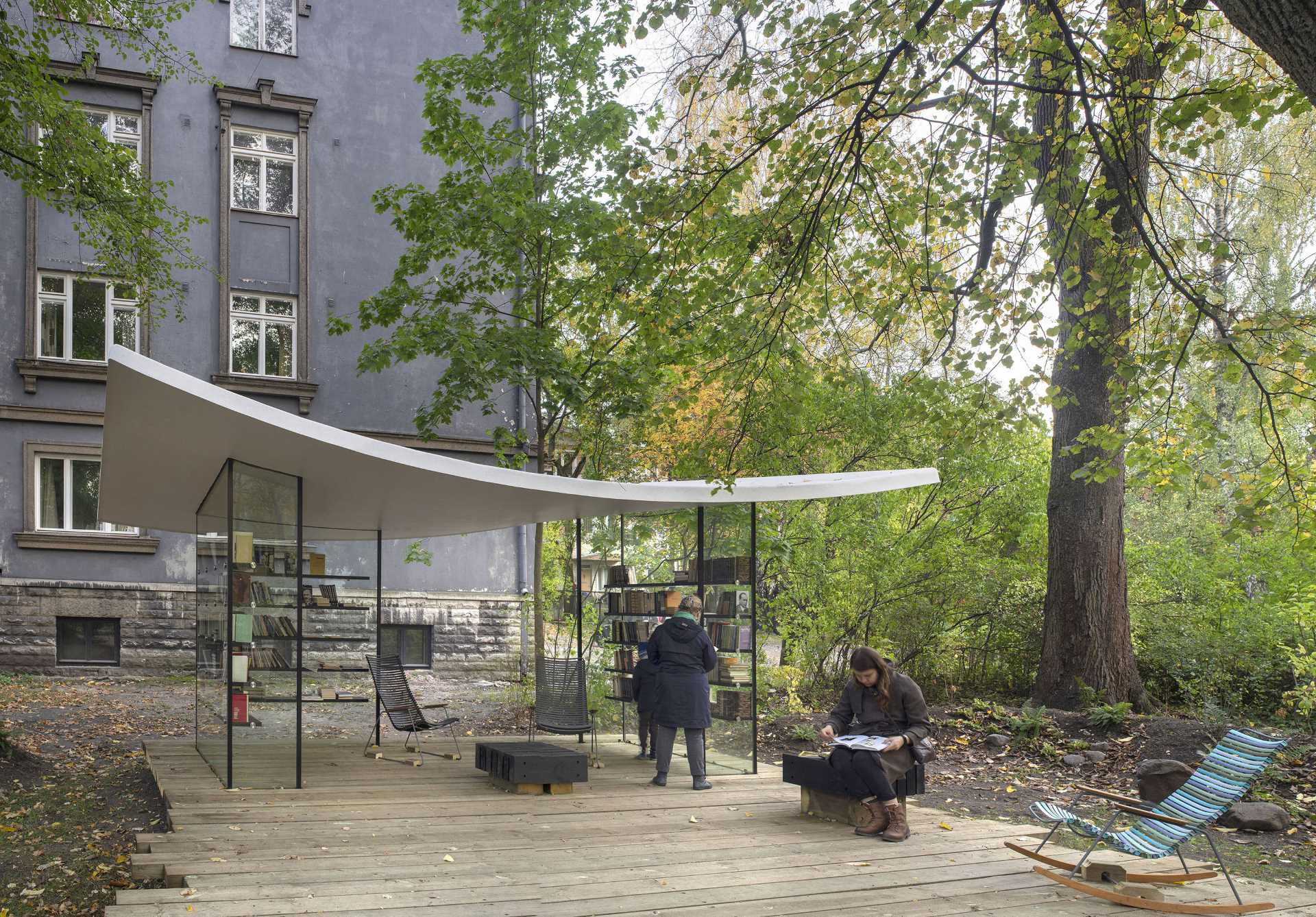 A small public library with glass walls and a white roof that's inspired by a sheet of paper.